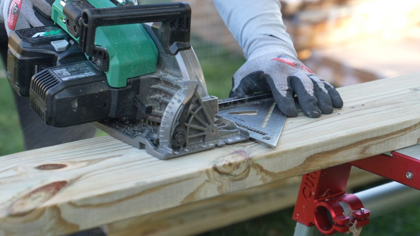 Professional carpenter cutting wood deck boards during installation